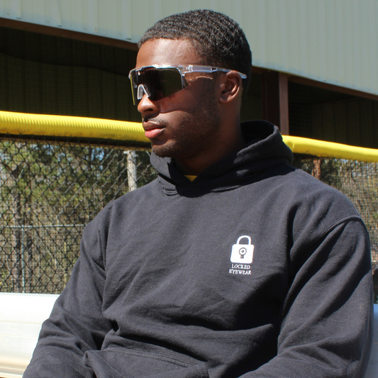 Image of Professional Baseball player sitting on baseball dugout bench wearing Locked Performance Baseball Sport Sunglasses to protect from UV Rays.