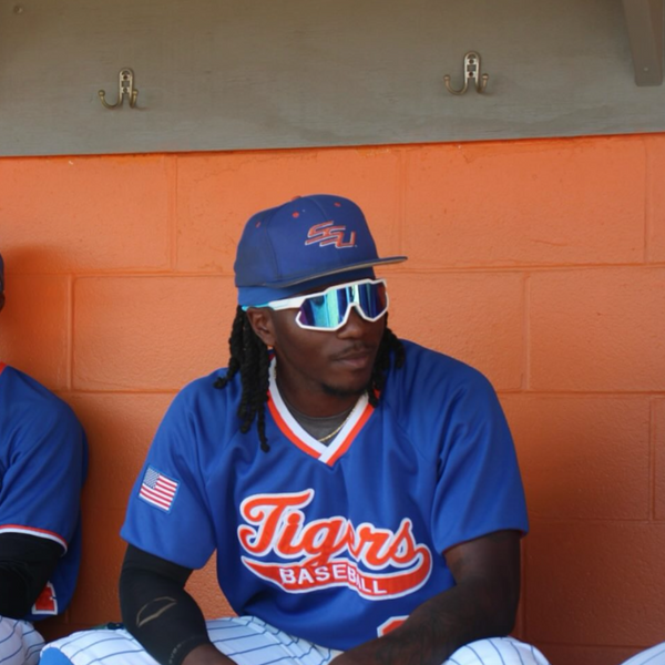 Elite baseball athlete in dugout wearing polarized baseball sunglasses built for game-day clarity