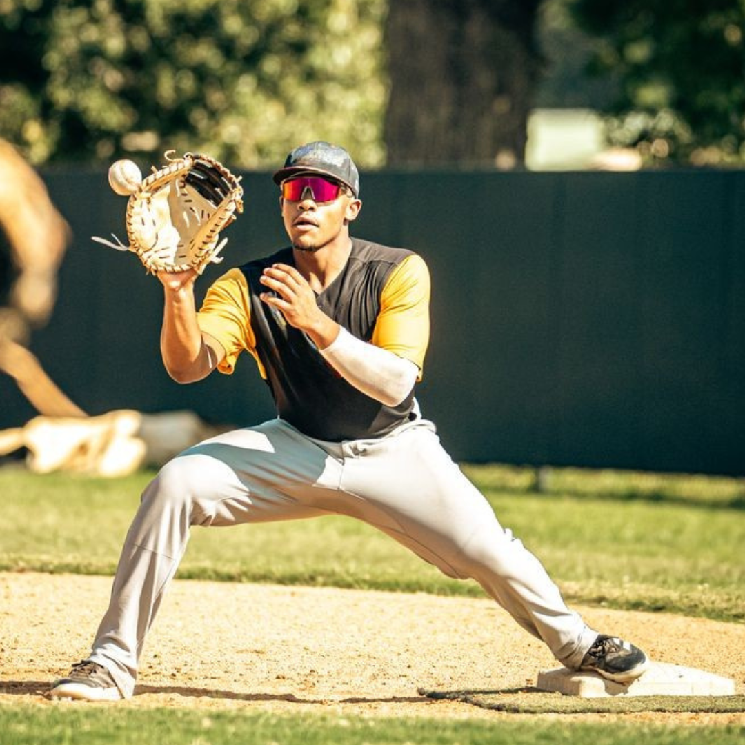 Locked Eyewear Revelation red lens baseball sunglasses by an infielder set in fielding position during a game, the non-polarized contrast lens keeping the ball sharp off the bat in bright conditions